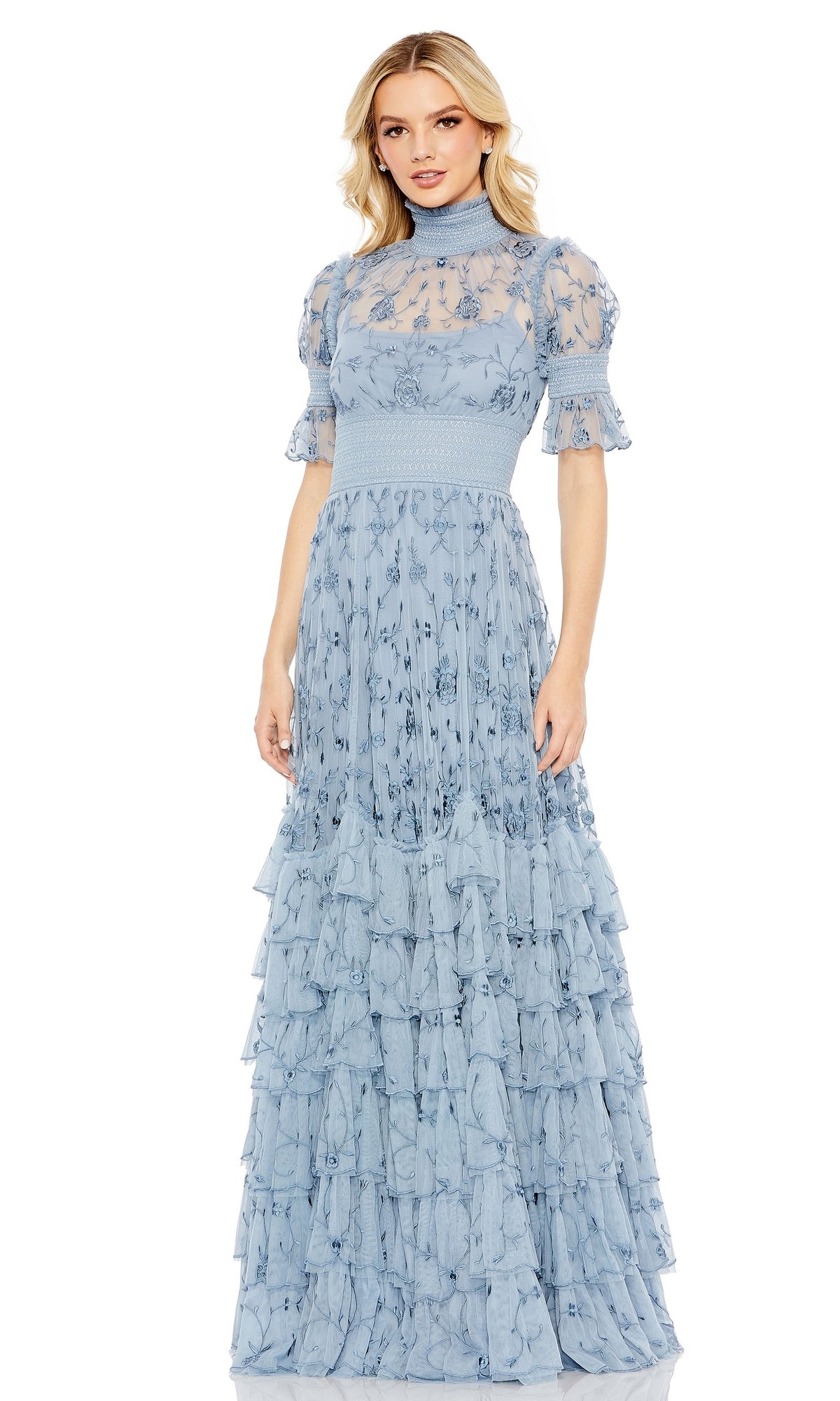 Woman in a light blue Mac Duggal 8005 short sleeve long formal dress featuring ruffled sleeves, high neckline, floral print, and a tiered ruffle skirt—an elegant choice for prom.
